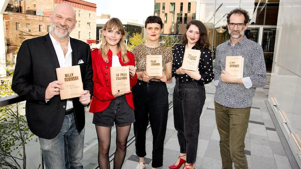 Deux hommes et trois femmes posent avec des trophées en bois en forme de livre.