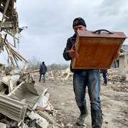 Un habitant se promène parmi les décombres de bâtiments résidentiels détruits par un tir de missile russe, près de la ville de Zolochiv, dans la région de Lviv le 9 mars 2023.