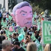 Des manifestants sont regroupés alors que flotte une tête gonflable géante de François Legault.