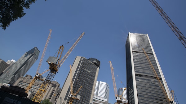 Des grues sur un chantier de construction, avec des édifices en arrière-plan, dont le 1000, de la Gauchetière.