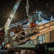 Des pompiers montent dans l'échelle de leur camion.