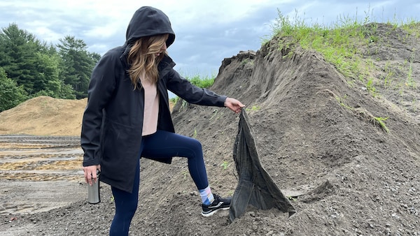 La journaliste Maude Montembeault fouille dans un amoncellement de sable de balayage.