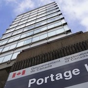 Enseigne du gouvernement fédéral devant un gratte-ciel vu en contre-plongée.