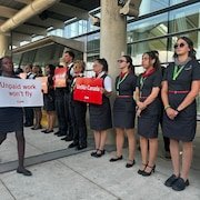 Des agentes de bord au piquet avec des pancartes dénonçant leurs conditions de travail.