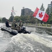 Des militaires en uniformes naviguent les eaux du canal Rideau à bord d'une embarcation gonflable.