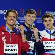 Trois nageurs montrent fièrement leurs médailles après la finale du 100 m papillon aux Mondiaux de sports aquatiques, à Singapour.