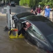 Un conducteur à bord d'une voiture dont l'arrière est plongé dans l'eau.