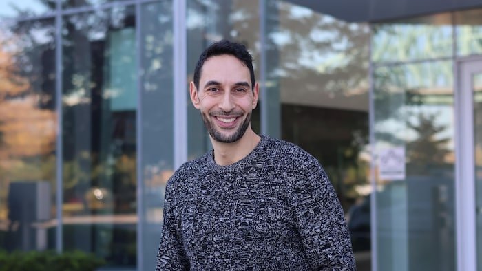 Éric Chacour sourit devant la Maison de Radio-Canada à Montréal.