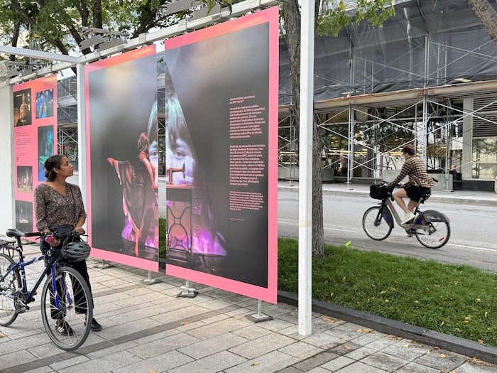 Une personne debout près de son vélo observe des affiches colorées.