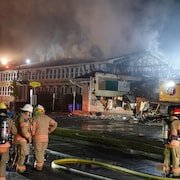 Des pompiers près de l'école endommagée par le feu.